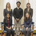 five students photographed in front of a window with three students standing and two sitting