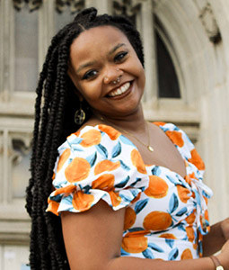 a woman with dark hair a flower dress on smiling outside