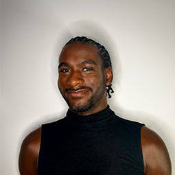 Portrait of a graduate in a sleeveless black top smiling in front of a plain background.