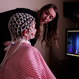 Student working with professor putting cap on child