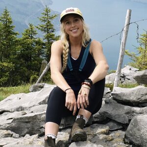 Blond girl sitting on a rock smiling with Mountain View behind her