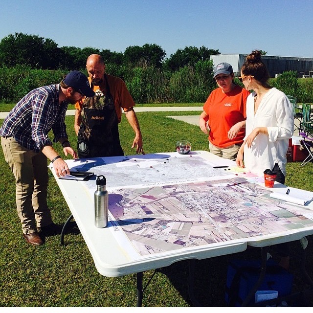 Monica Barra standing around a table with others looking at plans for an environmental project