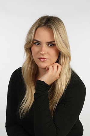 Portrait of a blonde student wearing a black top against a light studio background.