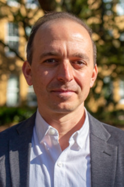 Guillermo Wippold smiles while wearing a white shirt and a gray blazer on The Horseshoe