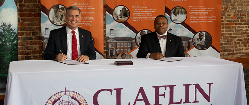 Two deans signing papers