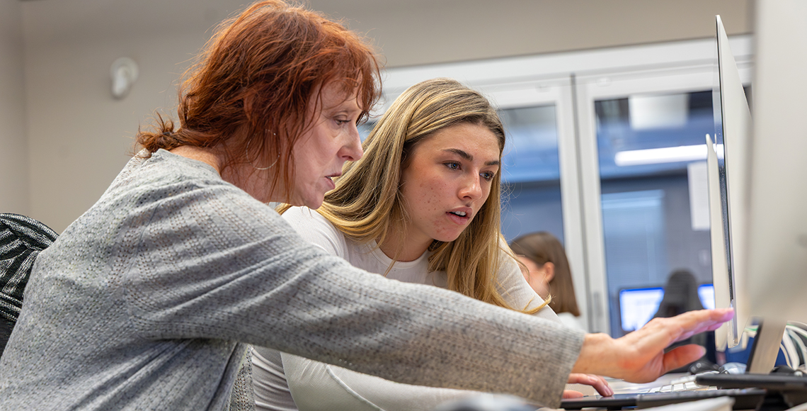 Instructor Elaine Eileen helps a student at the computer