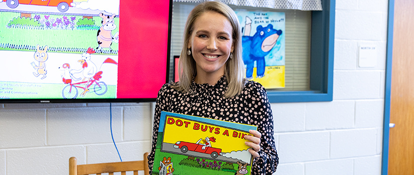 Rebekah Friedman holding a copy of Dot Buys a Bike