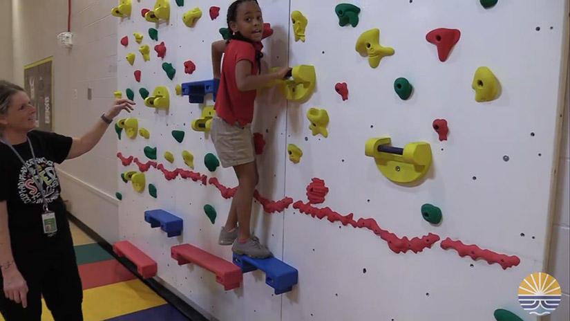 Heid leading a child to climb the wall