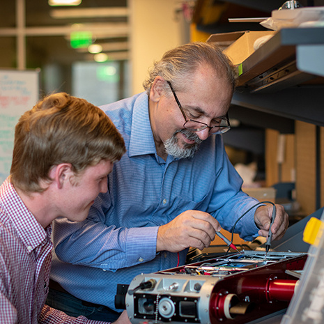 Ioannis Rekleitis works on a robot with a student.