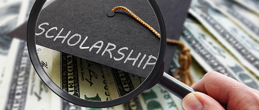 Scholarship graduation cap on money with magnifying glass