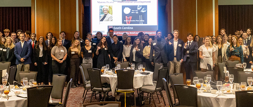 Students enrolled in HRSM 301 pose for a photo together at a business dinner etiquette seminar.