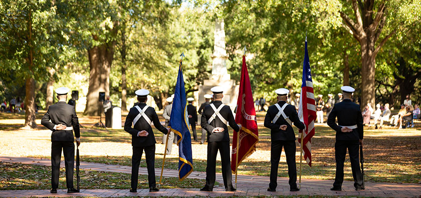 People in service uniforms stand with flags on the historic Horseshoe