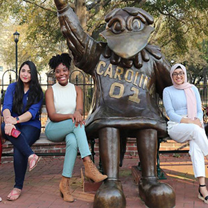 Students sitting next to a statue 