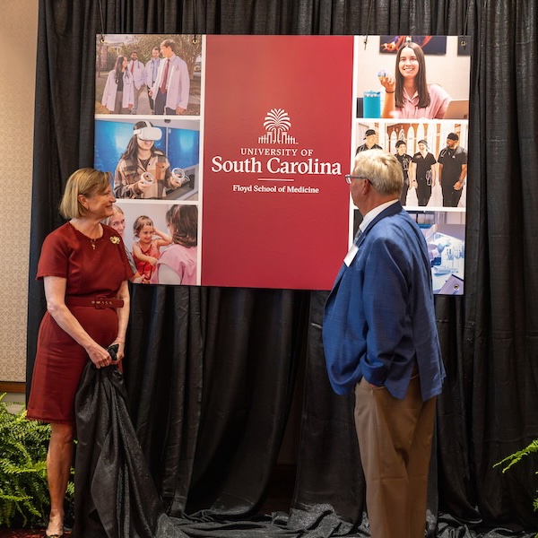 Two people unveil a sign reading 