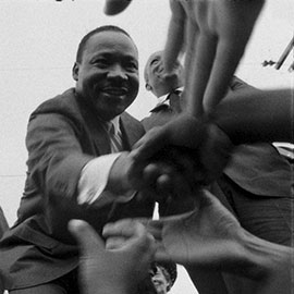 Martin Luther King Jr. clasps hands with attendees