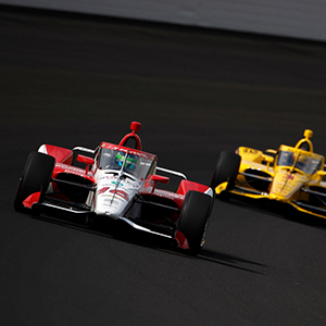 Two cars race on a track.