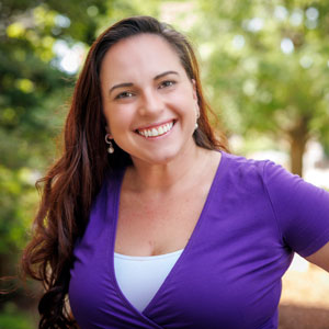 alumna Taylor Wilson poses in front of the State House in a purple shirt