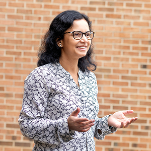 anita nag stands outside a brick building