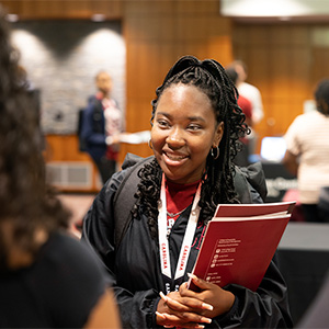 Student at Summer Seniors camp stands at table at academic fair