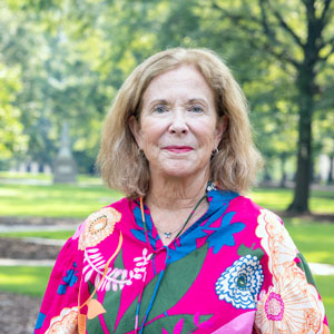 woman stands outside with grass and trees in the background