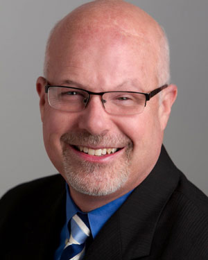 head and shoulders image of a man wearing glasses and a tie